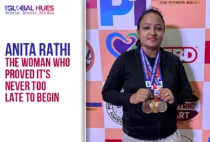 Woman with multiple medals around her neck posing in front of a sponsor backdrop; Anita Rathi poster shown on the left.