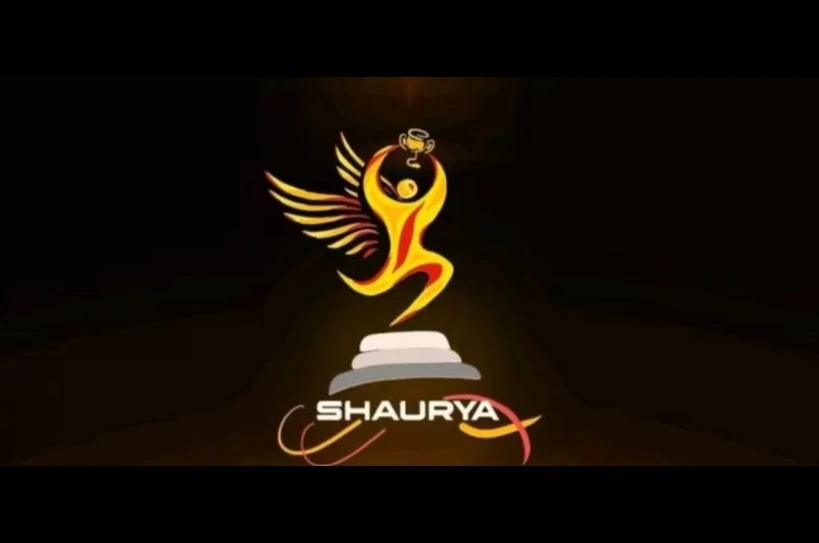 Logo of Shaurya: a stylized golden winged figure rising from a stepped pedestal, with the word 'SHAURYA' below.